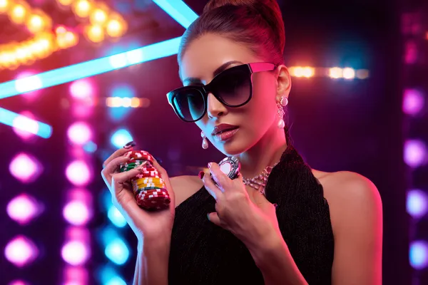 A young woman relaxing with her phone while dynamic casino elements float around her, illustrating the smooth mobile experience offered by the CHEZABET app.