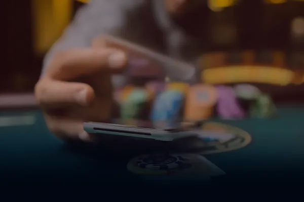A person using their device against a moody casino-themed background, illustrating the smooth re-entry process at CHEZABET.